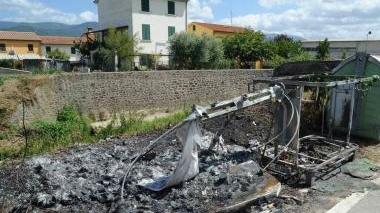 A sinistra, i cassonetti bruciati in via di Badia, tra Badia e Canapale. Sopra, un agente mostra una croce staccata dalla sede nel cimitero di Badia A lato, tombe danneggiate nel cimitero di Canapale