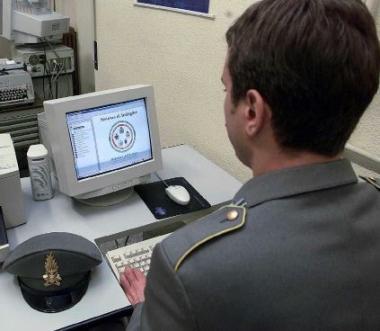 La sede dellAgenzia delle Entrate e pi&ugrave; a sinistra un finanziere lavora al computer 