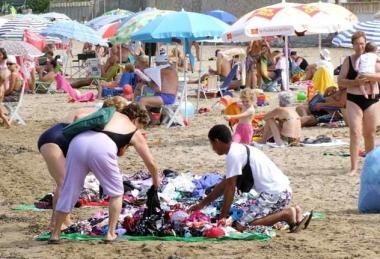 Un ambulante straniero vende costumi in spiaggia 