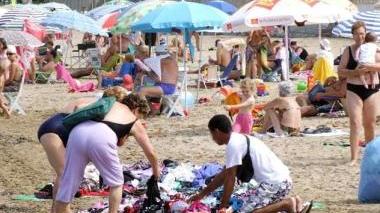 Un ambulante straniero vende costumi in spiaggia