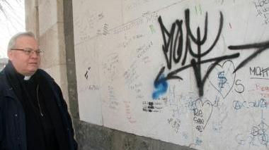 Monsignor Carlo Stancari davanti alla facciata della chiesa imbrattata di scritte