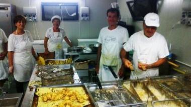 A destra i volontari al lavoro in cucina in occasione della Sagra del cunigliolo fritto a La Serra; sotto un esemplare di coniglio