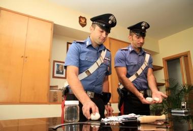 Due carabinieri mostrano la droga e altri oggetti sequestrati 
