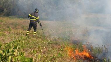 Sopra un vigile del fuoco in azione durante il rogo nella zona dell’H5 A destra l’elicottero della Regione getta l’acqua sopra le fiamme alte
