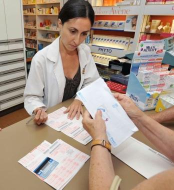 Una cliente nella farmacia Viti mostra i documenti Inps 