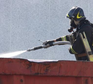 Di fianco un vigili del fuoco spengne le fiamme nel container A sinistra il getto sul soffitto 