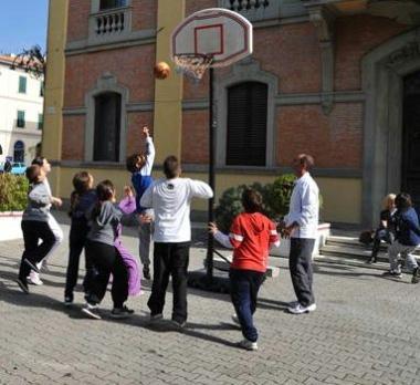 Bambini giocano a basket davanti al municipio    