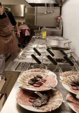 La cucina di un ristorante con fornelli e pietanze in primo piano  