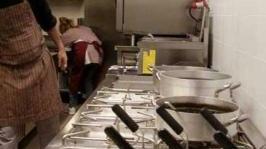 La cucina di un ristorante con fornelli e pietanze in primo piano
