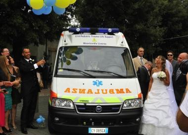 Gli sposi mentre brindano a fianco dellambulanza della Misericordia 