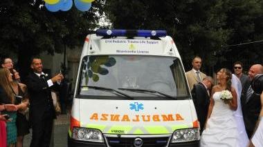 Gli sposi mentre brindano a fianco dell’ambulanza della Misericordia