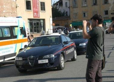 Un turista fotografa la scena del suicidio e qui sopra il corpo della ragazza coperto da un lenzuolo. Sotto, la folla di curiosi che si &egrave; attardata a vedere lopera dei volontari e degli inquirenti ai piedi della Torre 