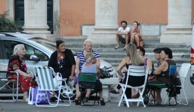 Piazza XX settembre intorno alle 18 di ieri con un gruppo di anziane intente a conversare, bambini che giocano a pallone, persone che si godono il bel tempo passeggiando   