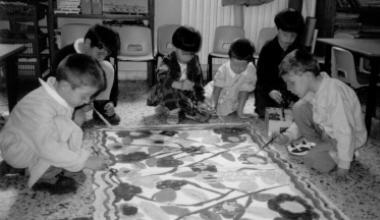 Alcuni bambini mentre dipingono sul pavimento di una scuola materna (foto d’archivio)