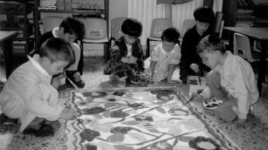 Alcuni bambini mentre dipingono sul pavimento di una scuola materna (foto d’archivio)