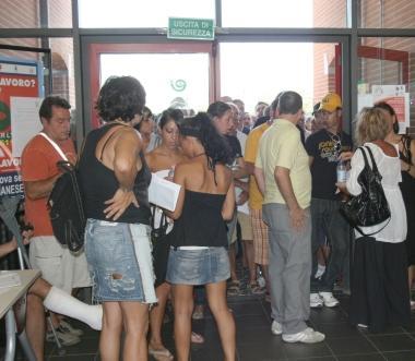 Decine di persone attendono in fila nel salone di un centro per limpiego  