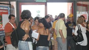 Decine di persone attendono in fila nel salone di un centro per l’impiego