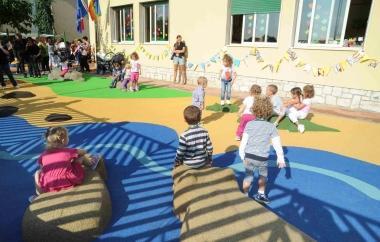 Alcuni bambini giocano, altri osservano sulle sedute in gomma