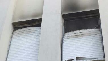 La finestra scassinata e annerita dal fumo, servita da ingresso ai ladri e il palazzo in cui c’è stato l’incendio