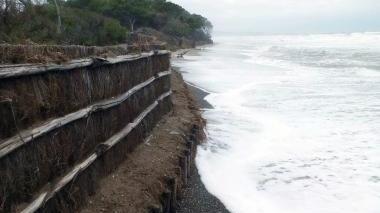 La spiaggia di Perelli sommersa dal mare e a destra un surfista che approfitta delle onde e il porto di Piombino rimasto chiuso per tutto il giorno