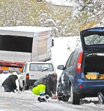 Automobilista impegnato a sistemare le catene da neve  