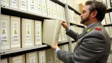 Sopra: un finanziere al lavoro in archivio per i controlli. Nel riquadro in alto: la compilazione della dichiarazione dei redditi