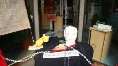 Protesta contro il Fisco incatenando una statua