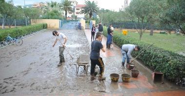 Giovani spalano fango sul viale che porta al polo scolastico, sotto negozianti e cittadini sgomberano gli oggetti rovinati dallacqua 
