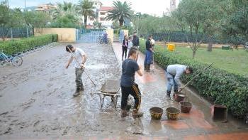 Giovani spalano fango sul viale che porta al polo scolastico, sotto negozianti e cittadini sgomberano gli oggetti rovinati dall’acqua