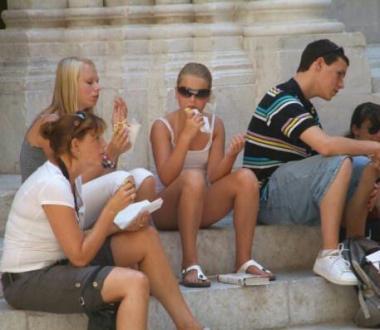 Turisti mentre mangiano un panino sui gradini di una chiesa    