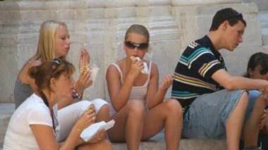 Turisti mentre mangiano un panino sui gradini di una chiesa