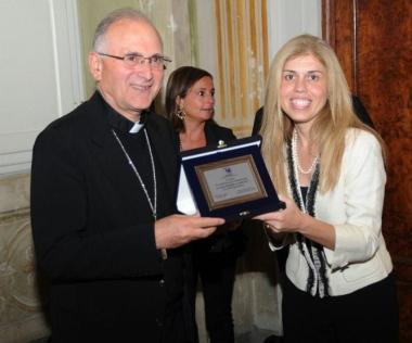 Michela Del Carlo, presidente Agesc, mentre premia il vescovo Castellani 