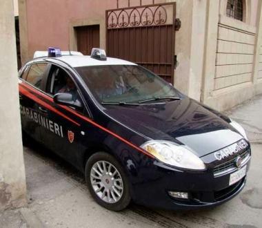 Unauto dei carabinieri e un militare che mostra la pistola sequestrata 