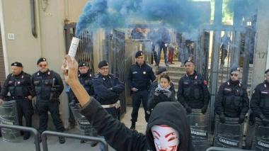 Uno studente accende un fumogeno davanti alle forze dell’ordine