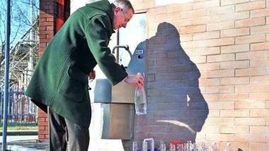 Un’anziano mentre lascia bottiglie di plastica per la raccolta differenziata