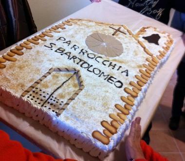 In alto la chiesa da restaurare Accanto la torta in onore della parrocchia di San Bartolomeo 