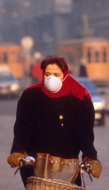 Una giovane donna in bicicletta indossa la mascherina antismog  