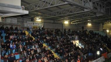 Il palasport gremito di pubblico; a destra l’intervento di Grillo