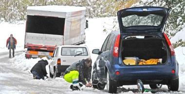 Automobilisti impegnati a montare le catene per poter proseguire la marcia su strade innevate 