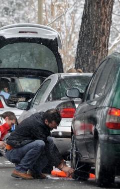 Automobilista mette le catene alla macchina  