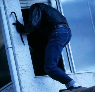 Un ladro in azione mentre entra da una finestra    