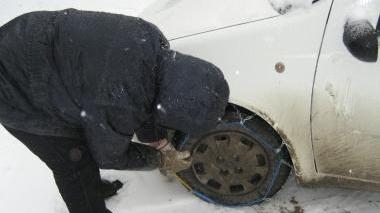 Un automobilista alle prese con il montaggio delle catene A sinistra la grande nevicata