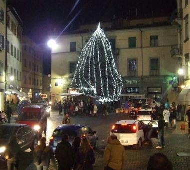 Una veduta di Castelnuovo con lalbero di natale illuminato e uno scorcio dei negozi del centro  