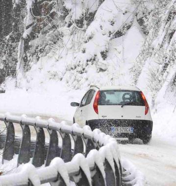 Unauto affronta una strada in salita durante una forte nevicata    