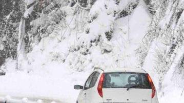 Un’auto affronta una strada in salita durante una forte nevicata