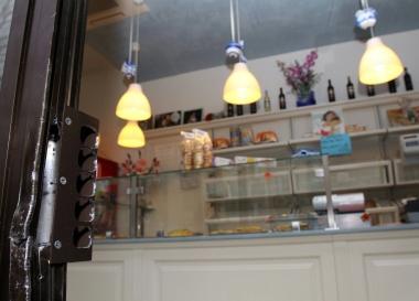 La serratura scardinata del negozio di alimentari, a destra la titolare 