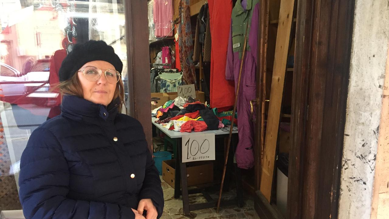 Francesca Bonelli davanti alla porta distrutta del suo negozio di abbigliamento