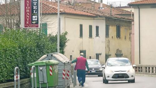Cassonetti in una curva pericolosa, con un pedone costretto a passare a pochi centimetri dalle auto in assenza di marciapiedi in uno dei tratti più pericolosi di via Sestini a Spazzavento