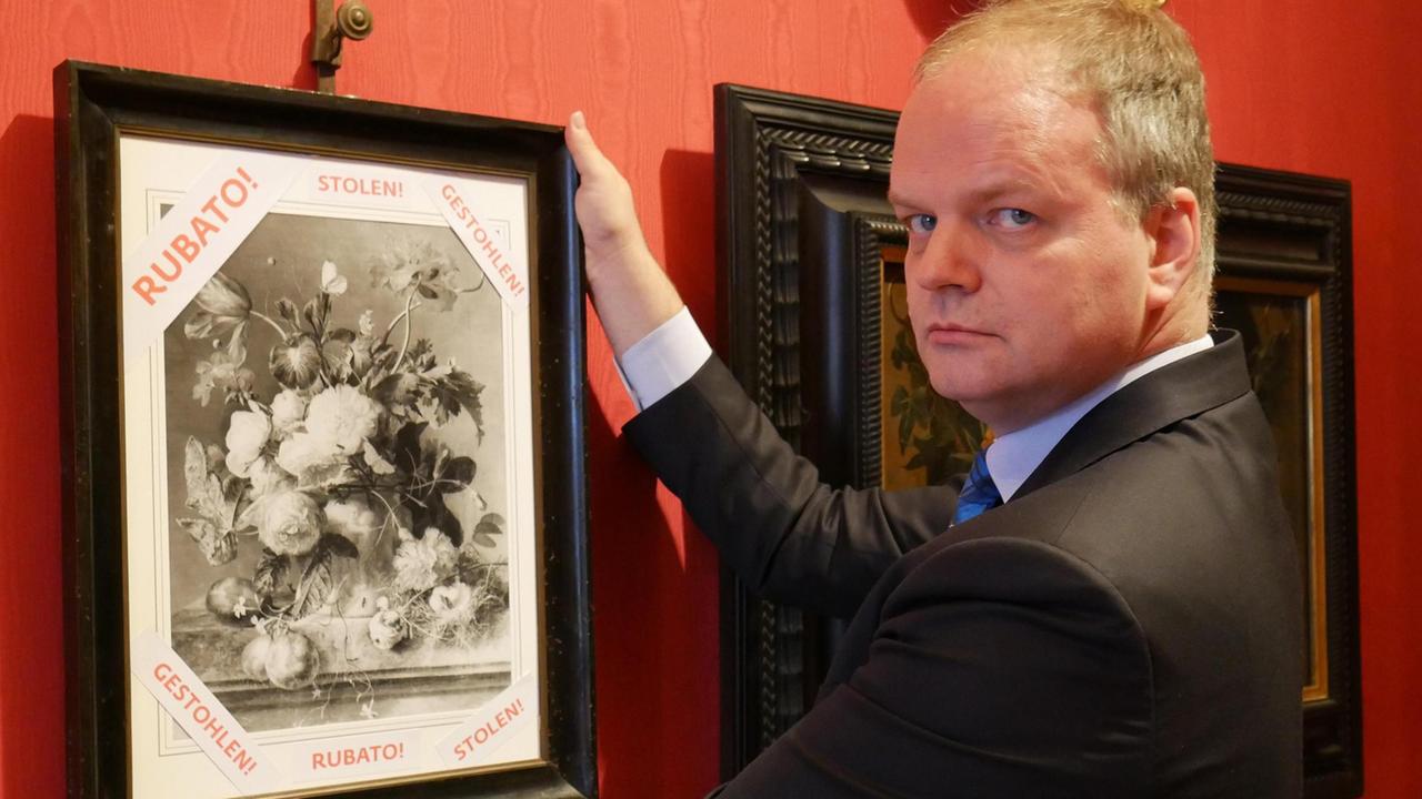 Il direttore degli Uffizi, Eike Schmidt, appende nella Galleria una riproduzione del quadro rubato