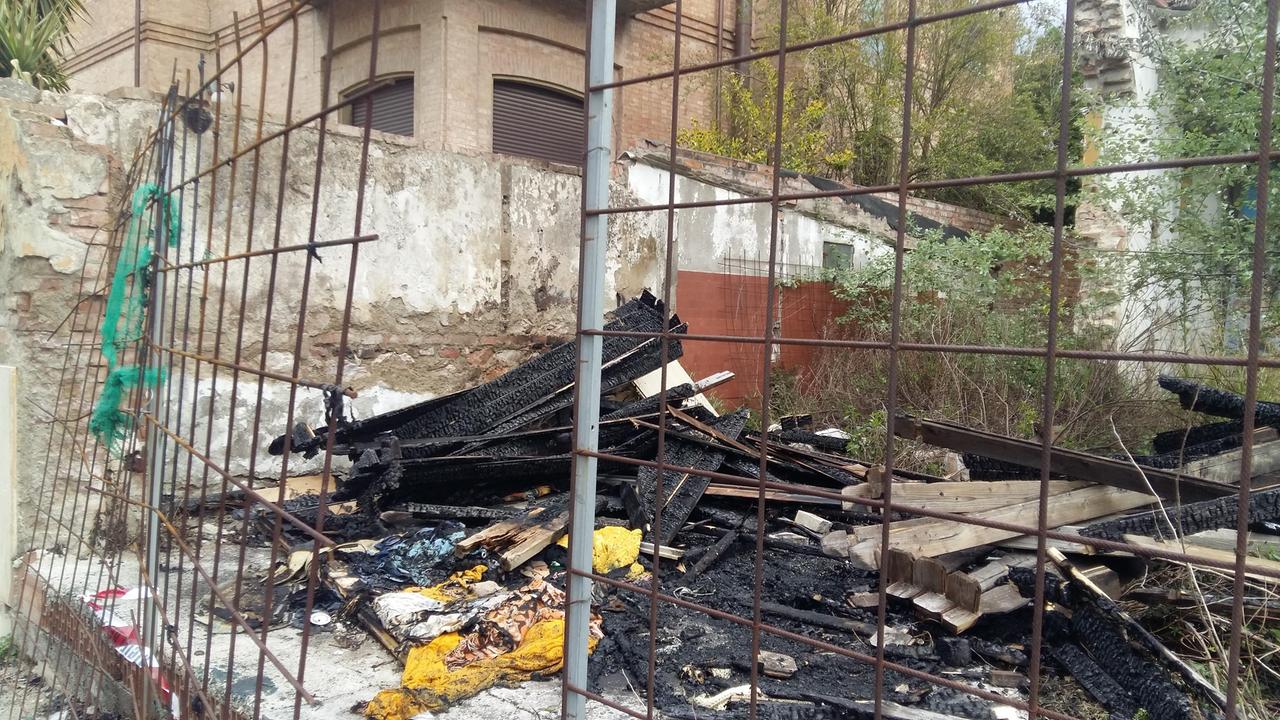 I resti dell'incendio a Palazzo Boman e il varco nella rete arrugginita